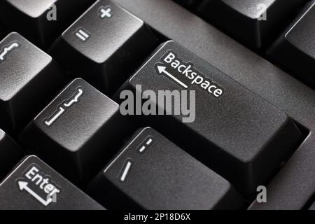 Black plastic standard English computer keyboard close up macro shot top side view backspace button. Stock Photo