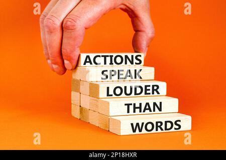 Actions speak louder words symbol. Concept words Actions speak louder than words on wooden blocks. Beautiful orange table orange background. Business Stock Photo