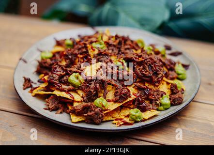 Mexican nachos with beef and chilli on wooden table Stock Photo