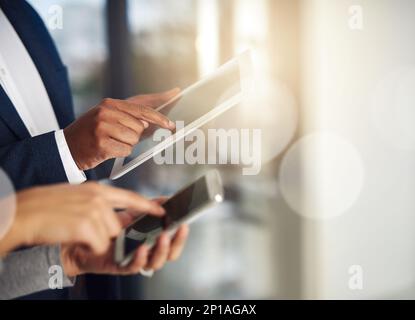 Modern business demands cutting edge technology. Cropped shot of businesspeople using their tablets and phones at work. Stock Photo