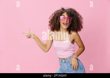 Woman with curly afro hair model poses on a pink background in a pink  T-shirt, free movement and dance, look into the camera, smile with teeth  and Stock Photo - Alamy