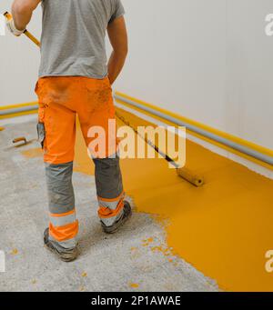 epoxy flooring applicator performs painting works with polyurethane epoxy mortar Stock Photo