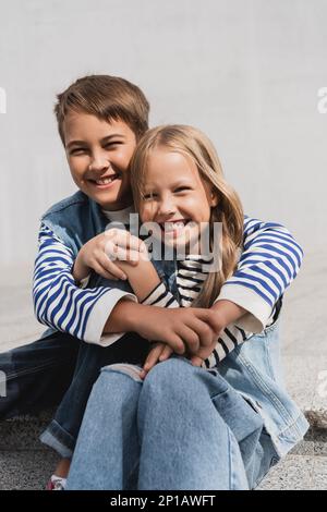 happy preteen boy in hugging well dressed girl while sitting on stairs,stock image Stock Photo