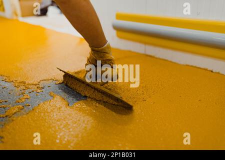 epoxy flooring applicator performs painting works with polyurethane epoxy mortar Stock Photo