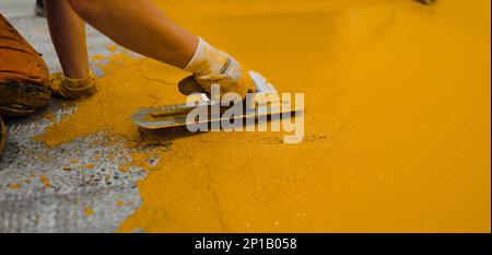 Professional construction worker applying floor paint or a new layer for a epoxy cast coating floor Stock Photo