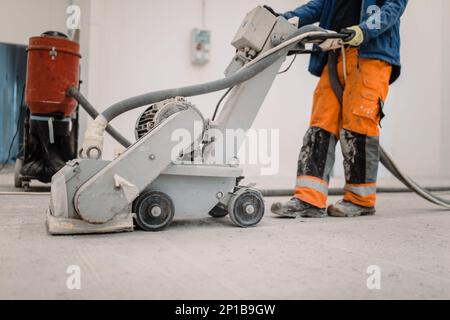 Workers grind the concrete floor at the construction site. Prepares the floor for polyurethane mortar Stock Photo