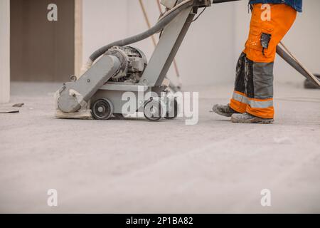 Workers grind the concrete floor at the construction site. Prepares the floor for polyurethane mortar Stock Photo