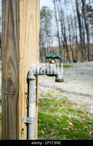 Clean water tap attached to a wooden post at a campground Stock Photo