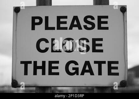 A sign at the dockyard requesting that people shut the gate Stock Photo