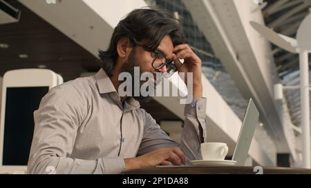 Pensive Indian businessman typing on laptop remote working internet concentrated arabian man manager analyzing digital data create business plan using Stock Photo