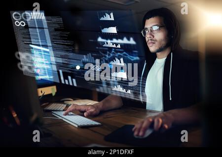 Pulling the strings through programming. Shot of a young hacker cracking a computer code in the dark. Stock Photo