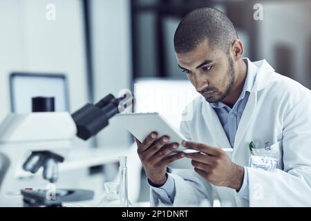 Using his tablet for research purposes. Shot of a scientist recording his findings on a digital tablet. Stock Photo