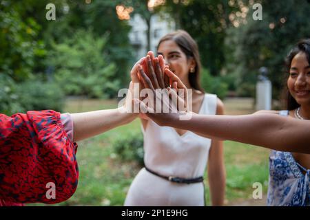 Multi ethnic group of female friends join hands together, international women's day concept. Stock Photo
