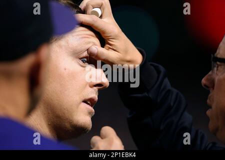 Colorado Rockies' Charlie Blackmon, left, shows to trainer Scott Gehret  where a foul ball hit his batting helmet as he stood in the on-deck circle,  during the third inning of the team's