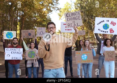 Group of people with posters protesting against climate change on city street Stock Photo