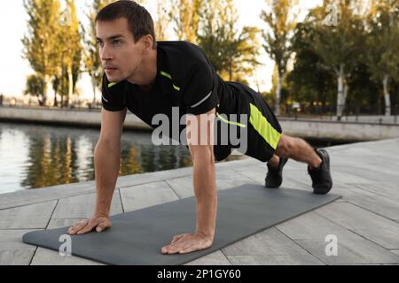 Sporty man doing straight arm plank exercise near river Stock Photo