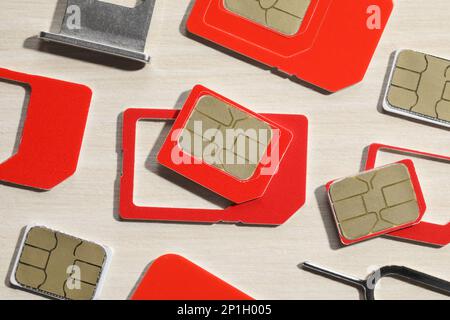 Different SIM cards, ejector and tray on wooden background, flat lay Stock Photo