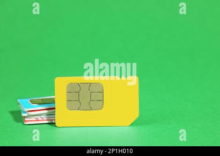 Different SIM cards on green background. Space for text Stock Photo