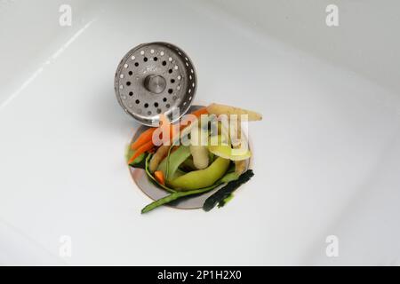 Vegetable scraps in kitchen sink with garbage disposal Stock Photo