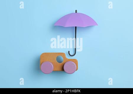 Bright umbrella and toy car on light blue background, flat lay Stock Photo