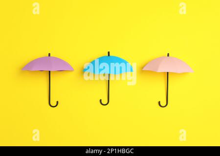 Bright toy umbrellas on yellow background, flat lay Stock Photo