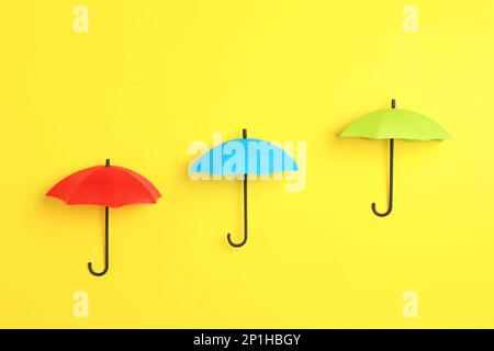 Bright toy umbrellas on yellow background, flat lay Stock Photo