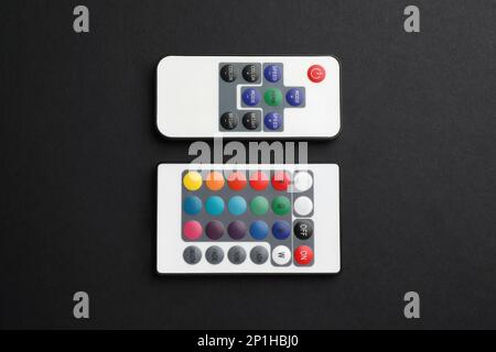 Remote controls on black background, flat lay Stock Photo