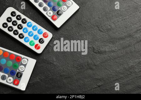 Remote controls on black table, flat lay. Space for text Stock Photo