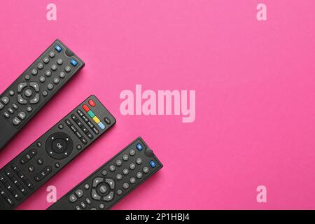 Remote controls on pink background, flat lay. Space for text Stock Photo