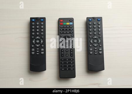 Modern tv remote controls on white wooden table, flat lay Stock Photo