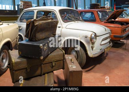 ZELENOGORSK, RUSSIA - JANUARY 27, 2023: A bunch of old suitcases against the background of the Soviet small car 'Zaporozhets' ZAZ-966. Museum of retro Stock Photo