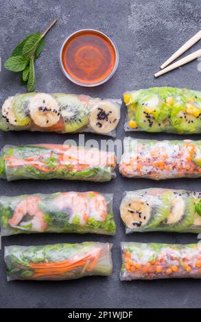 Fresh assorted spring rolls set. Handmade asian/Chinese spring rolls. Rustic concrete background. Spring rolls with shrimps, vegetables, fruits. Top Stock Photo