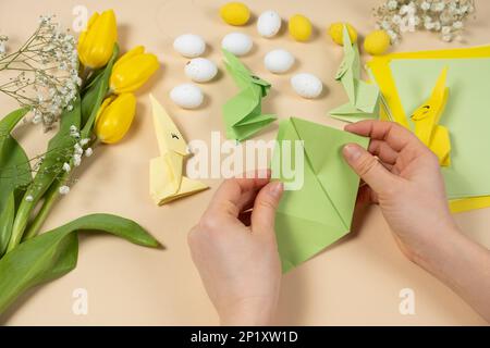 Handicrafts from paper for Easter - origami, making figurines of Easter bunnies, hands close-up Stock Photo