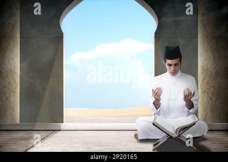 Muslim man sitting while raised hands and praying in the mosque Stock Photo