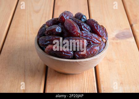Date fruits in wooden bowl,on wooden table Stock Photo