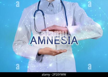 Doctor demonstrating virtual model of word AMNESIA on light blue background, closeup Stock Photo