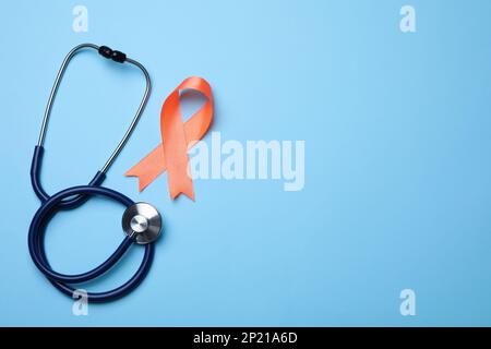 Orange ribbon and stethoscope on light blue background, flat lay with space for text. Multiple sclerosis awareness Stock Photo