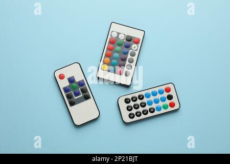 Different remote controls on light blue background, flat lay Stock Photo