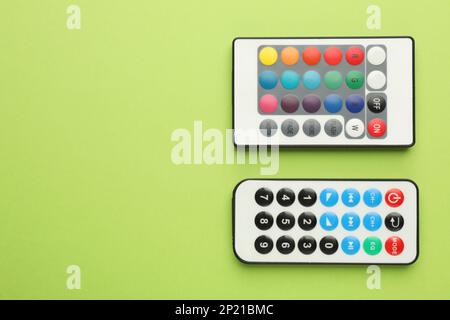 Remote controls on light green background, flat lay. Space for text Stock Photo