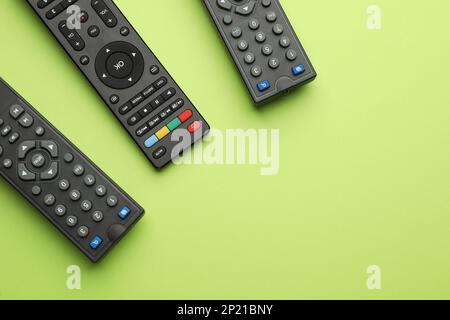 Remote controls on light green background, flat lay. Space for text Stock Photo