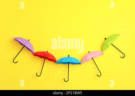 Bright toy umbrellas on yellow background, flat lay Stock Photo