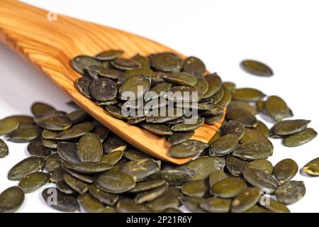 Dried pumpkin seeds on a wooden spoon against white background Stock Photo