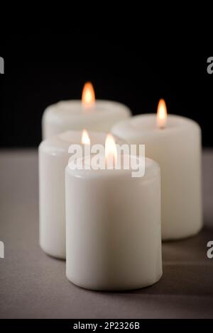 set of burning white candles on the shelf with black background Stock Photo