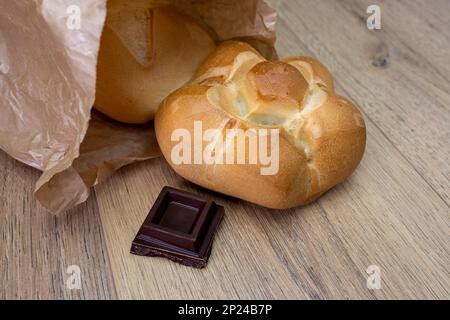 ypical Milan tradition bread "michetta" with dark chocolate square on wooden table Stock Photo