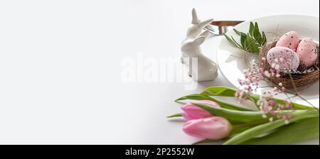 Easter background with colored Easter eggs and blooming flowers, tulips. Two Easter Bunnies. Easter composition. Easter. Banner. copy space Stock Photo