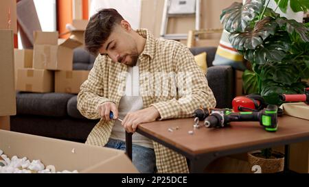 Young arab man repairing table using screwdriver at new home Stock Photo