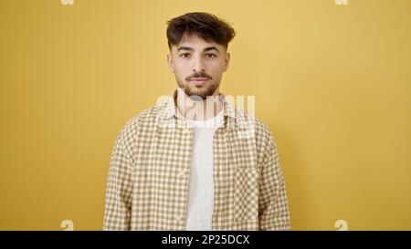 Young arab man standing with relaxed expression over isolated yellow background Stock Photo