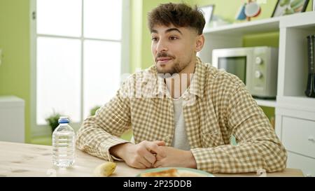 Young arab man having breakfast speaking at home Stock Photo