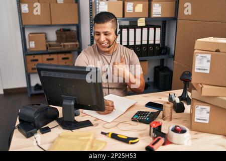 Hispanic young man working at small business ecommerce smiling happy and positive, thumb up doing excellent and approval sign Stock Photo