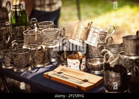 Lot of antique metal glass holders at a flea market. Many old ornate cup holders at a garage sale Stock Photo